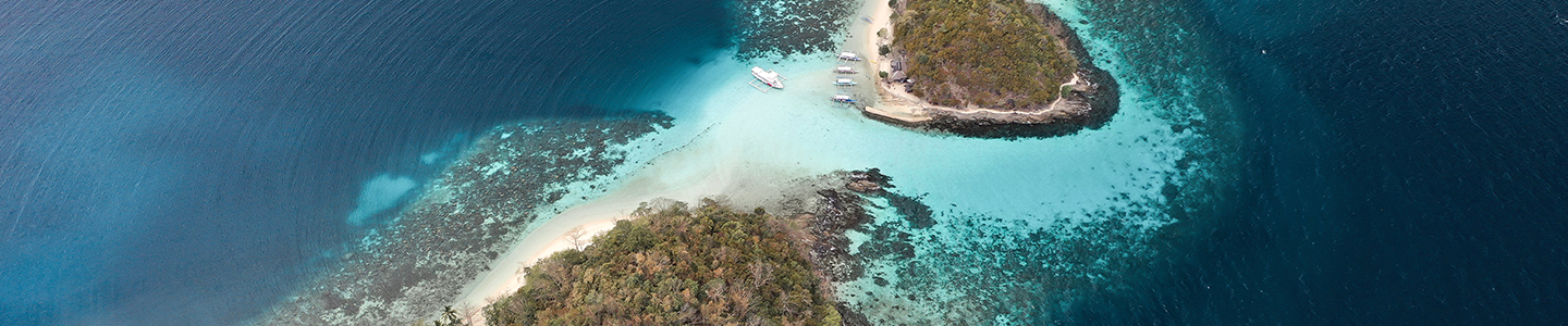 Photograph of two islands in the Philippines with sand beaches and boats docked at the coast